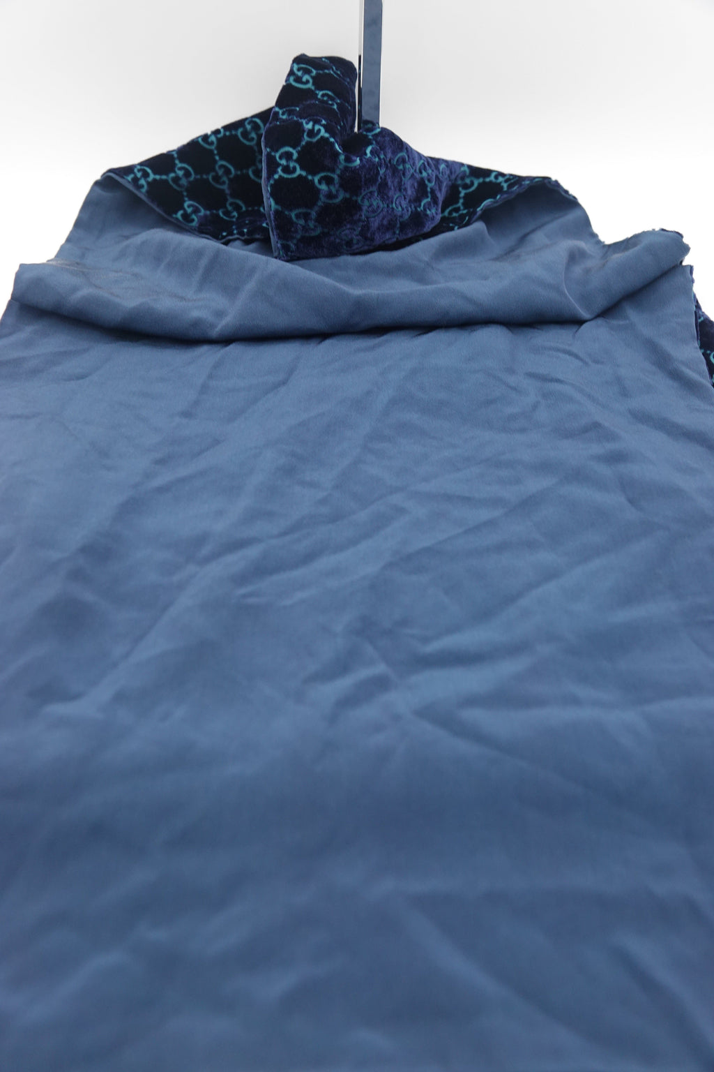 Blue textured fabric with a patterned corner on a white background