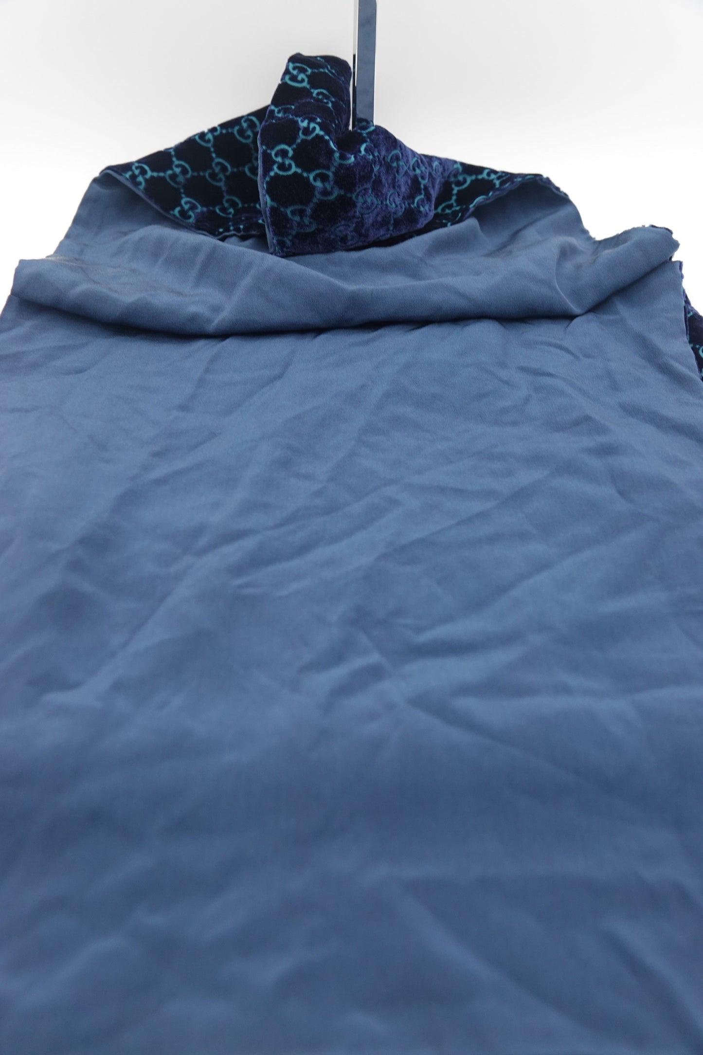 Blue textured fabric with a patterned corner on a white background