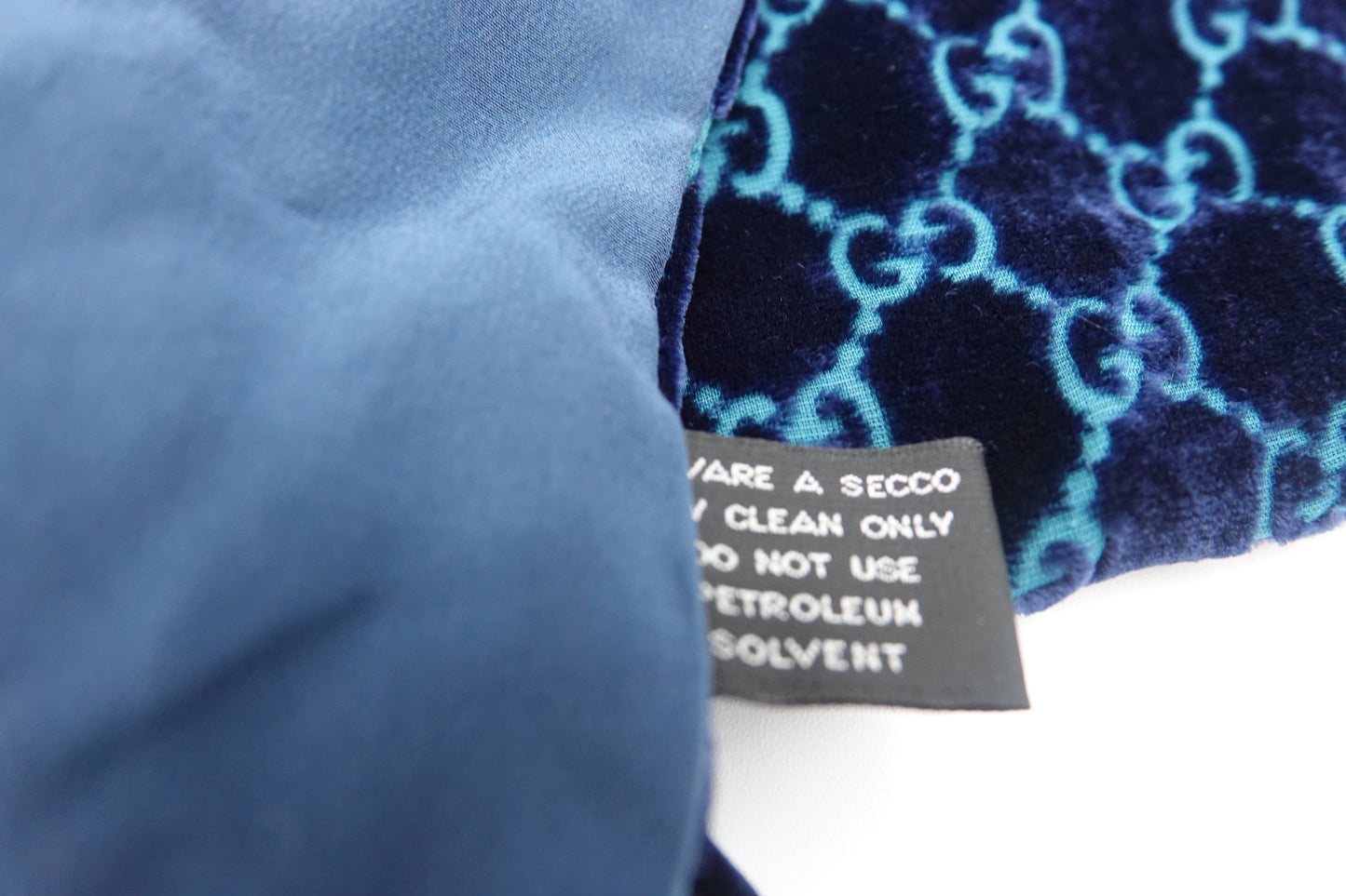 Close-up of a blue fabric with a patterned tag on a white background
