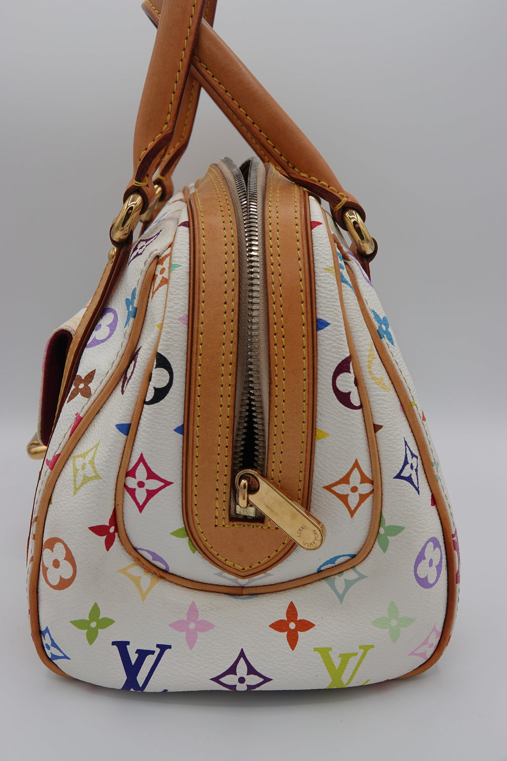 Designer handbag with multicolor pattern and brown leather accents on a white background