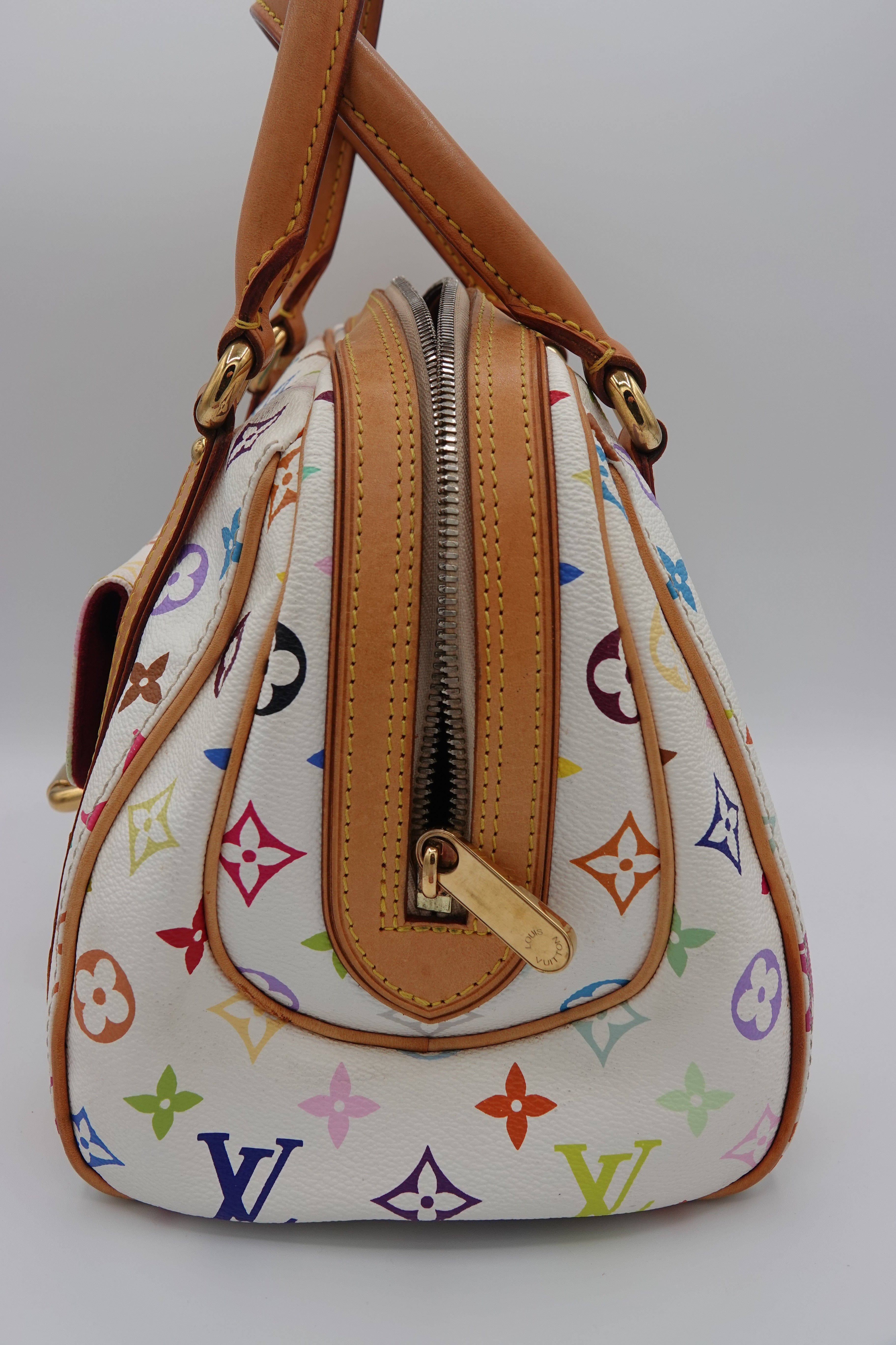 Designer handbag with multicolor pattern and brown leather accents on a white background
