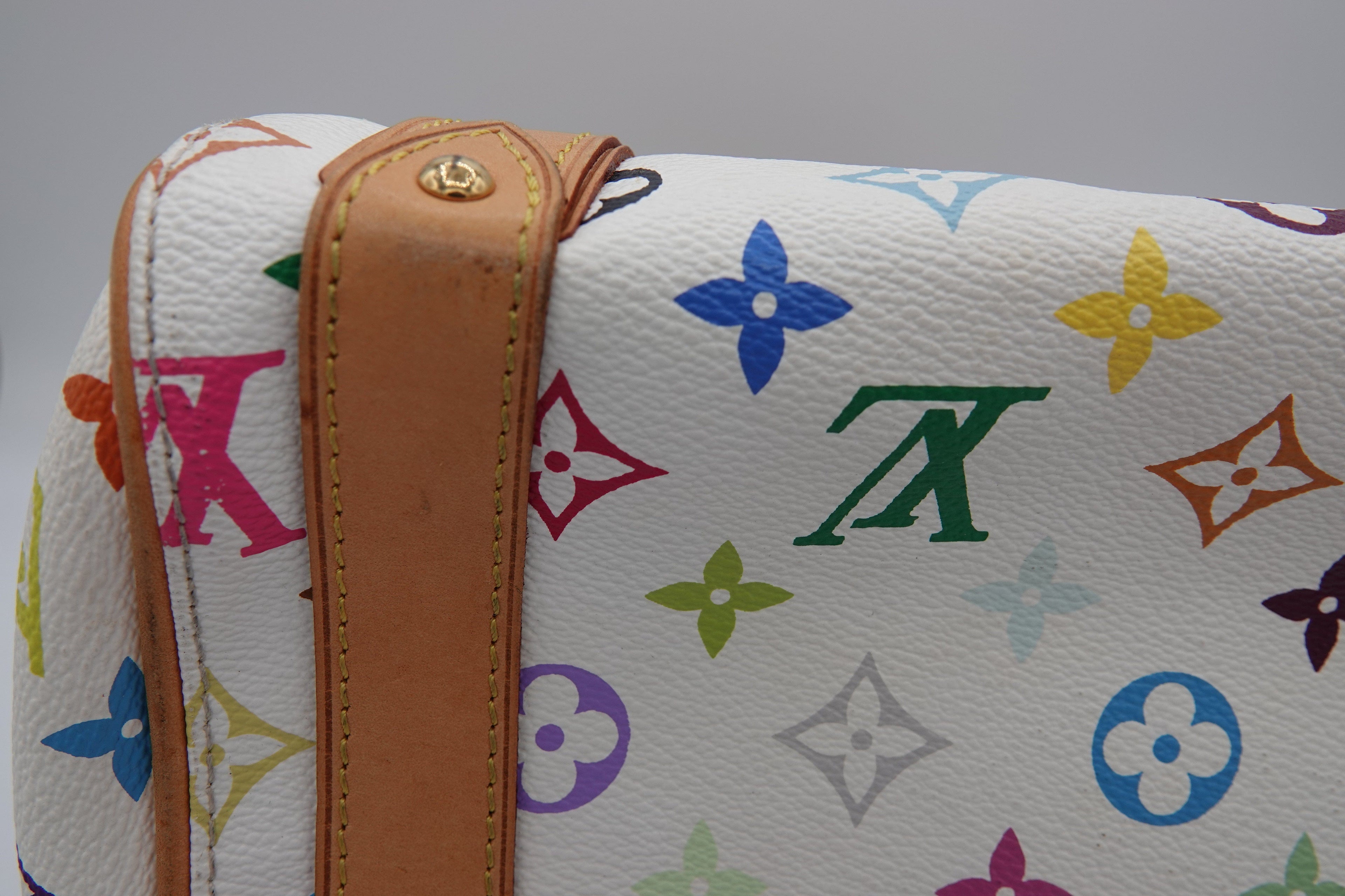 Designer handbag with colorful monogram pattern on a gray background