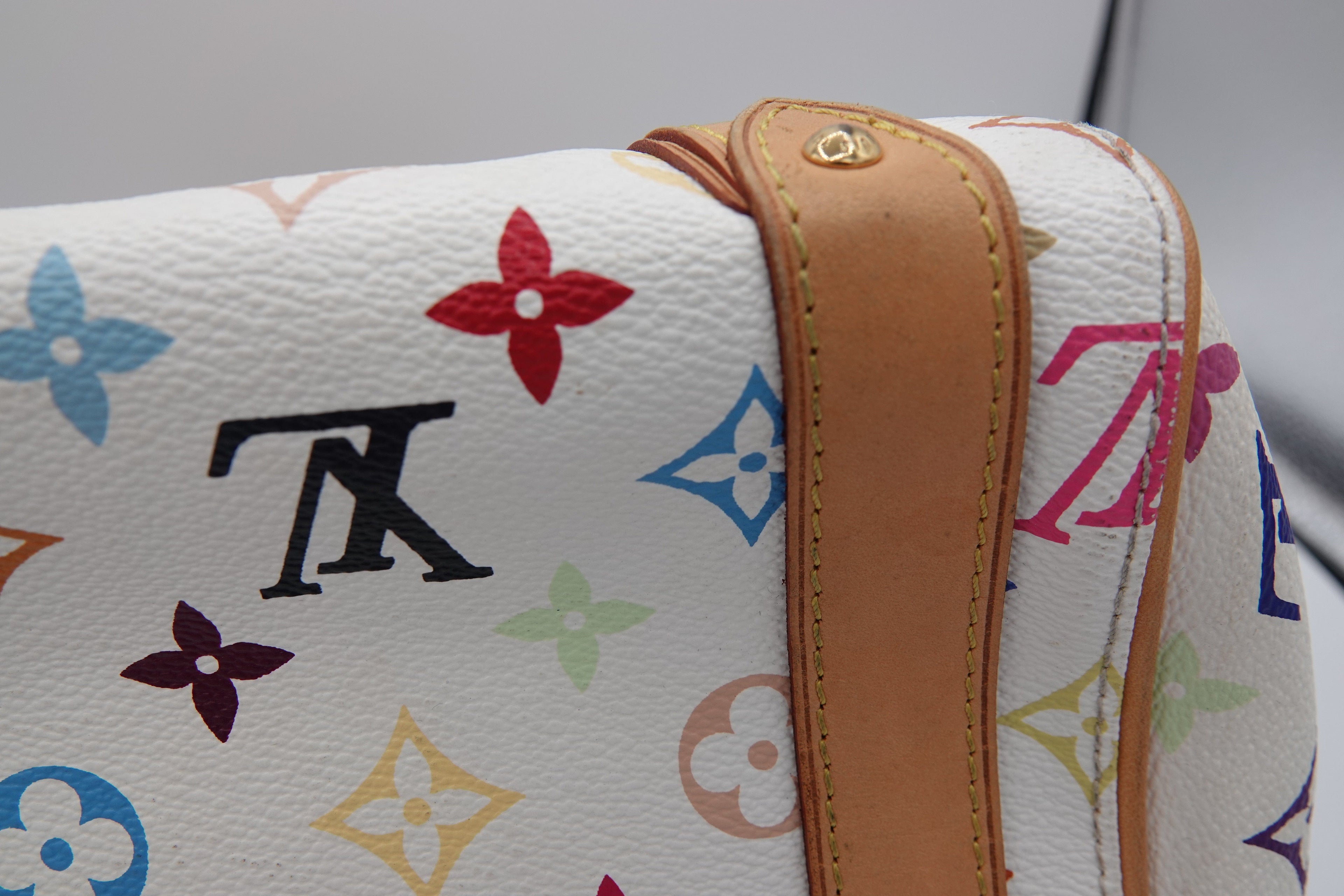 Close-up of a Louis Vuitton handbag with multicolor monogram pattern and brown leather strap.