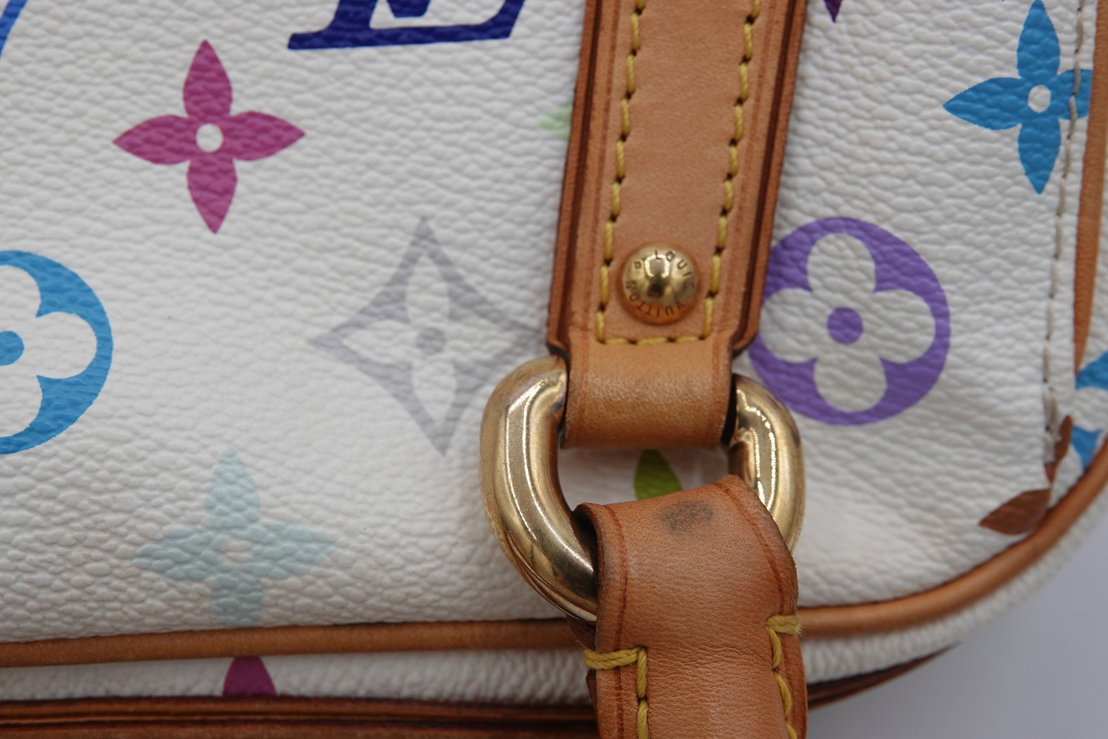 Close-up of a handbag with floral pattern and brown leather strap.