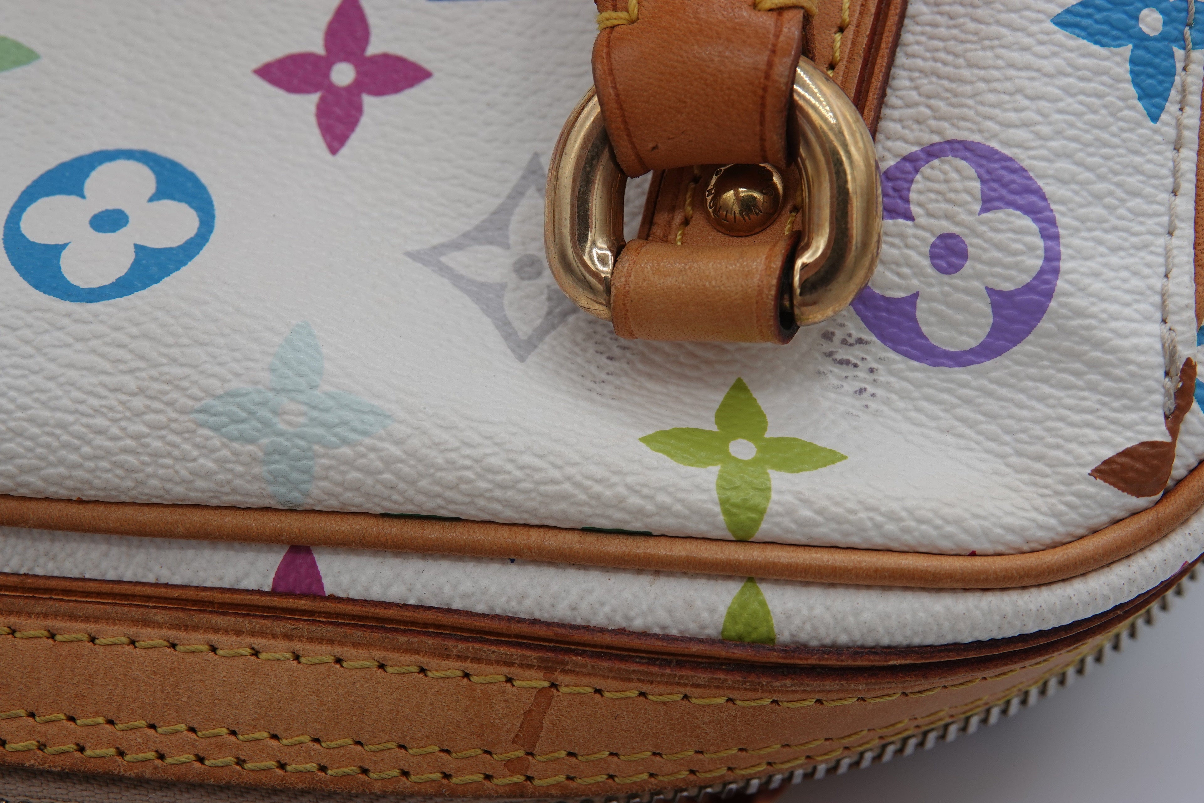 Close-up of a handbag with floral patterns and brown leather strap.