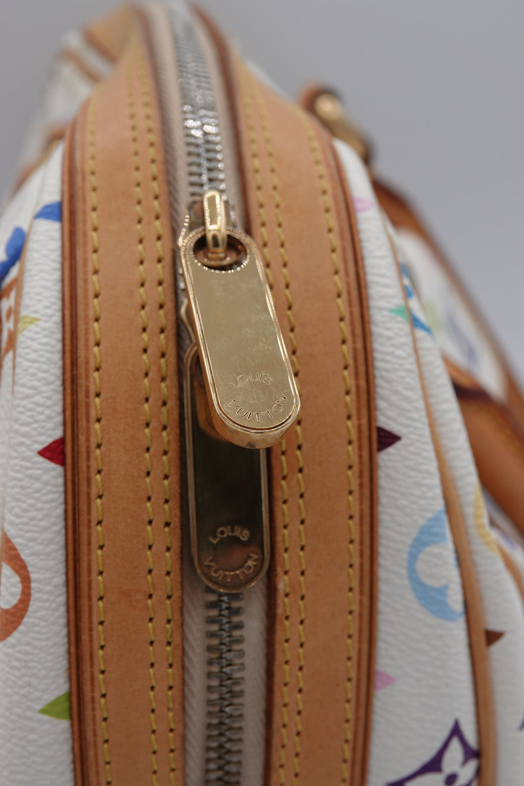 Close-up of a patterned handbag with a gold zipper on a light gray background