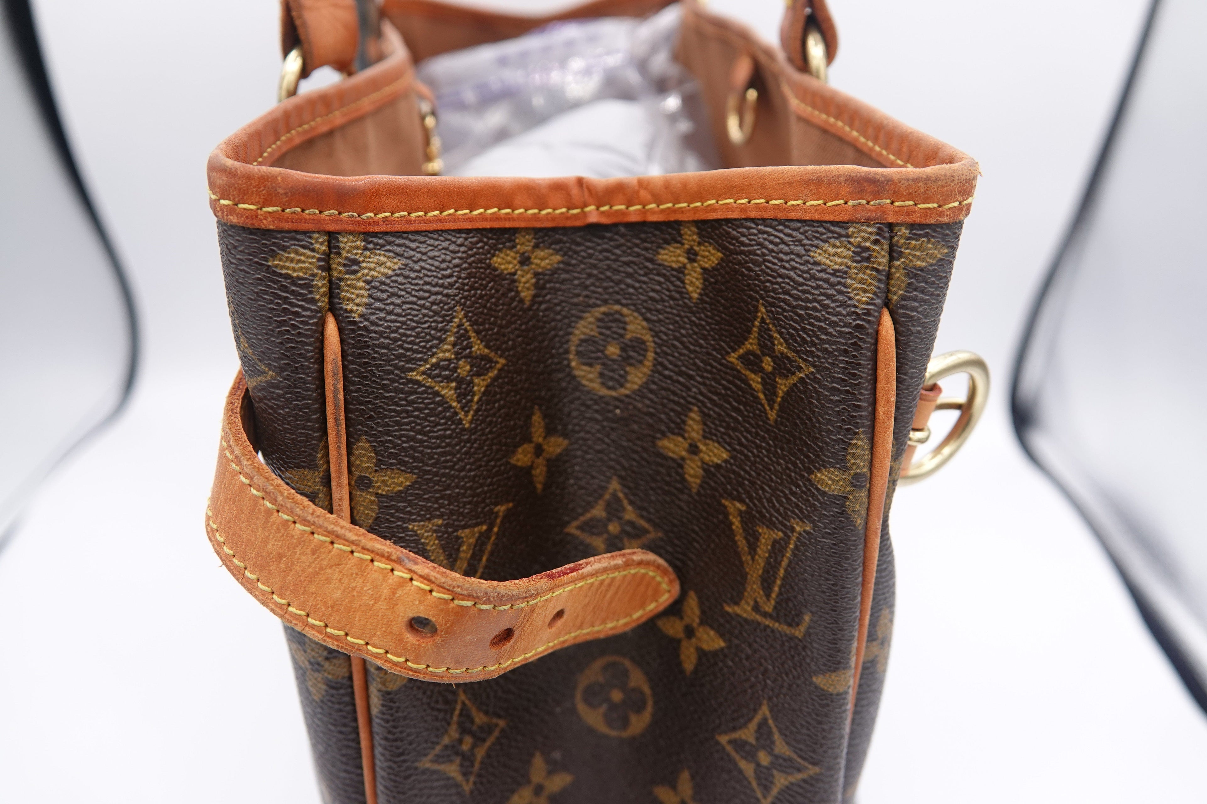 Close-up of a brown leather handbag with visible brand logo on a white background