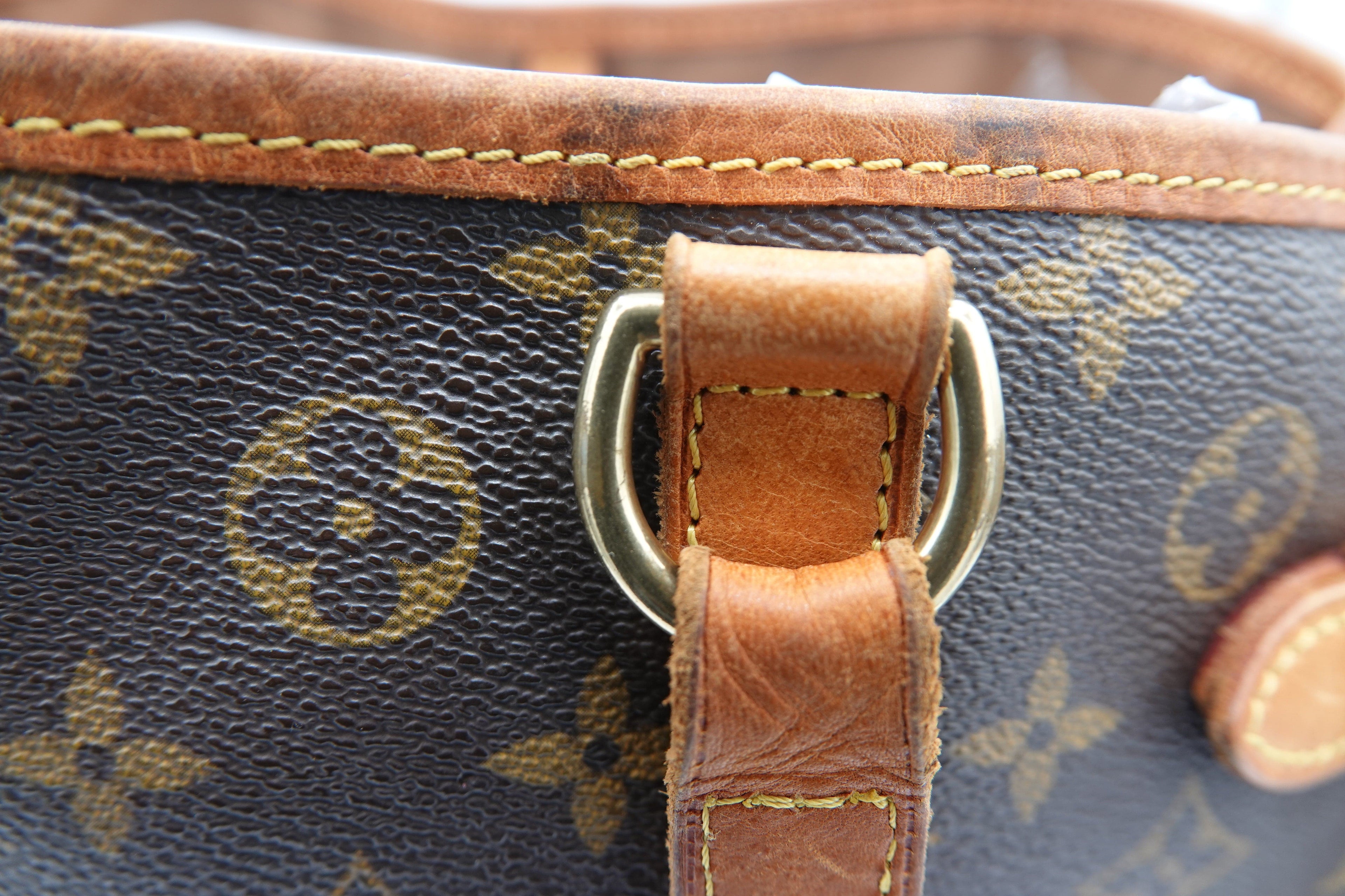 Close-up of a Louis Vuitton handbag with monogram pattern and brown leather handle.