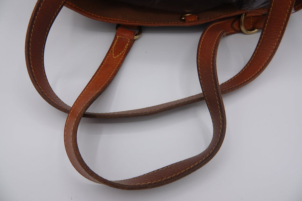 Close-up of a brown leather handbag with visible stitching on a white background