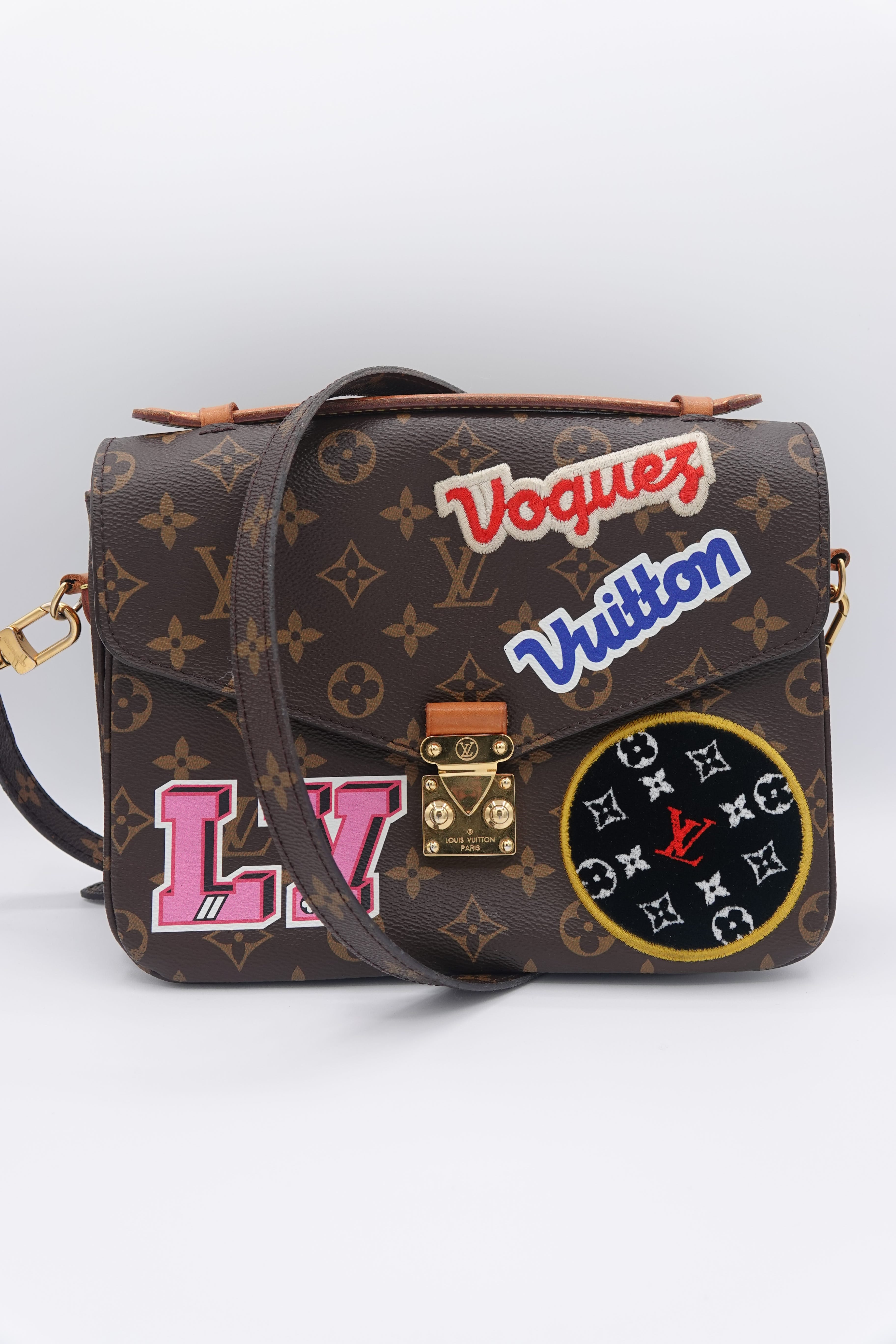 Designer handbag with colorful patches on a white background