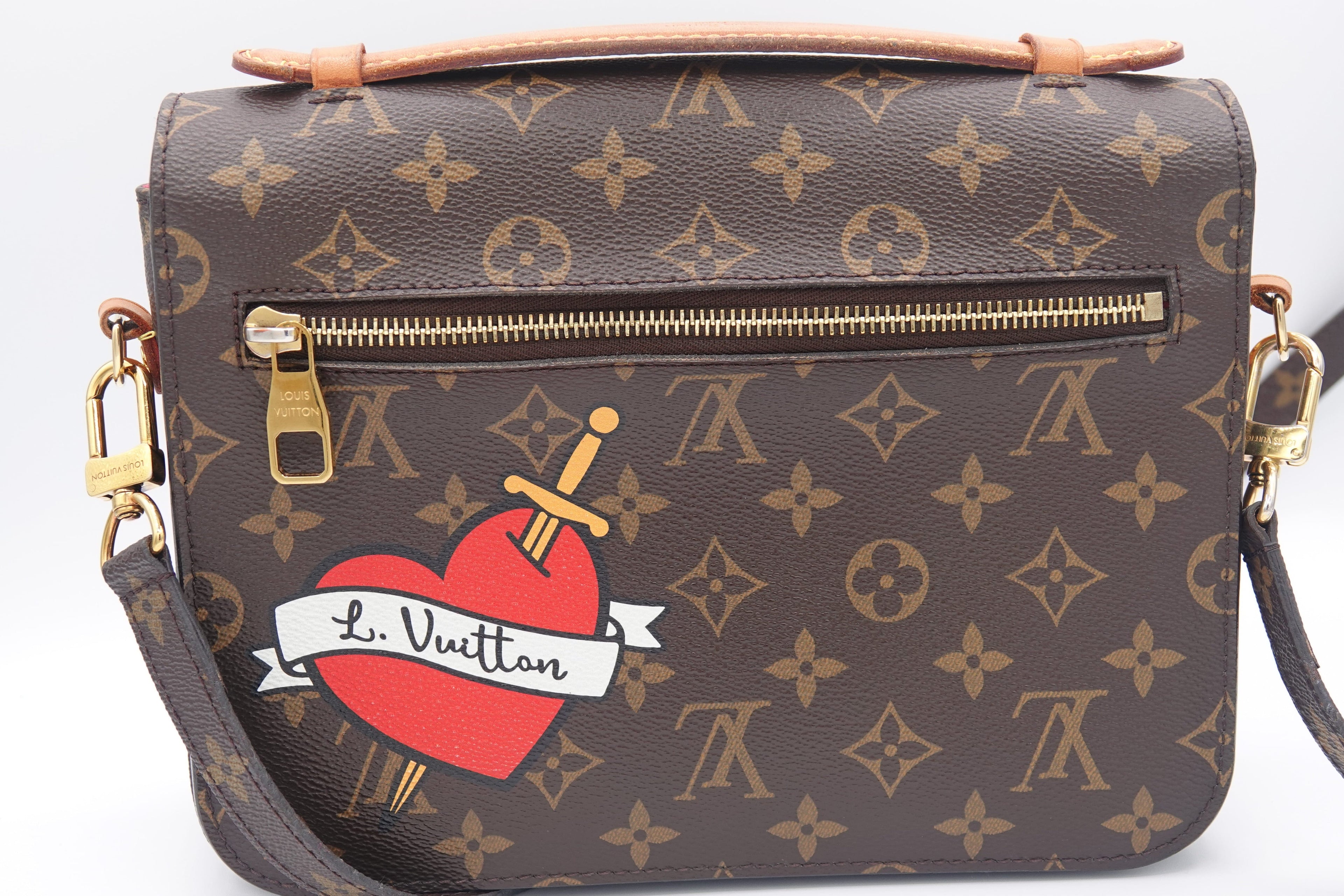Designer handbag with a heart and sword design on a white background