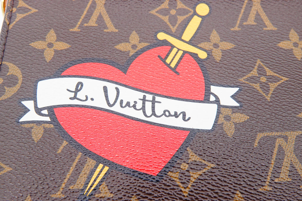 Louis Vuitton monogram bag with a red heart and sword design.