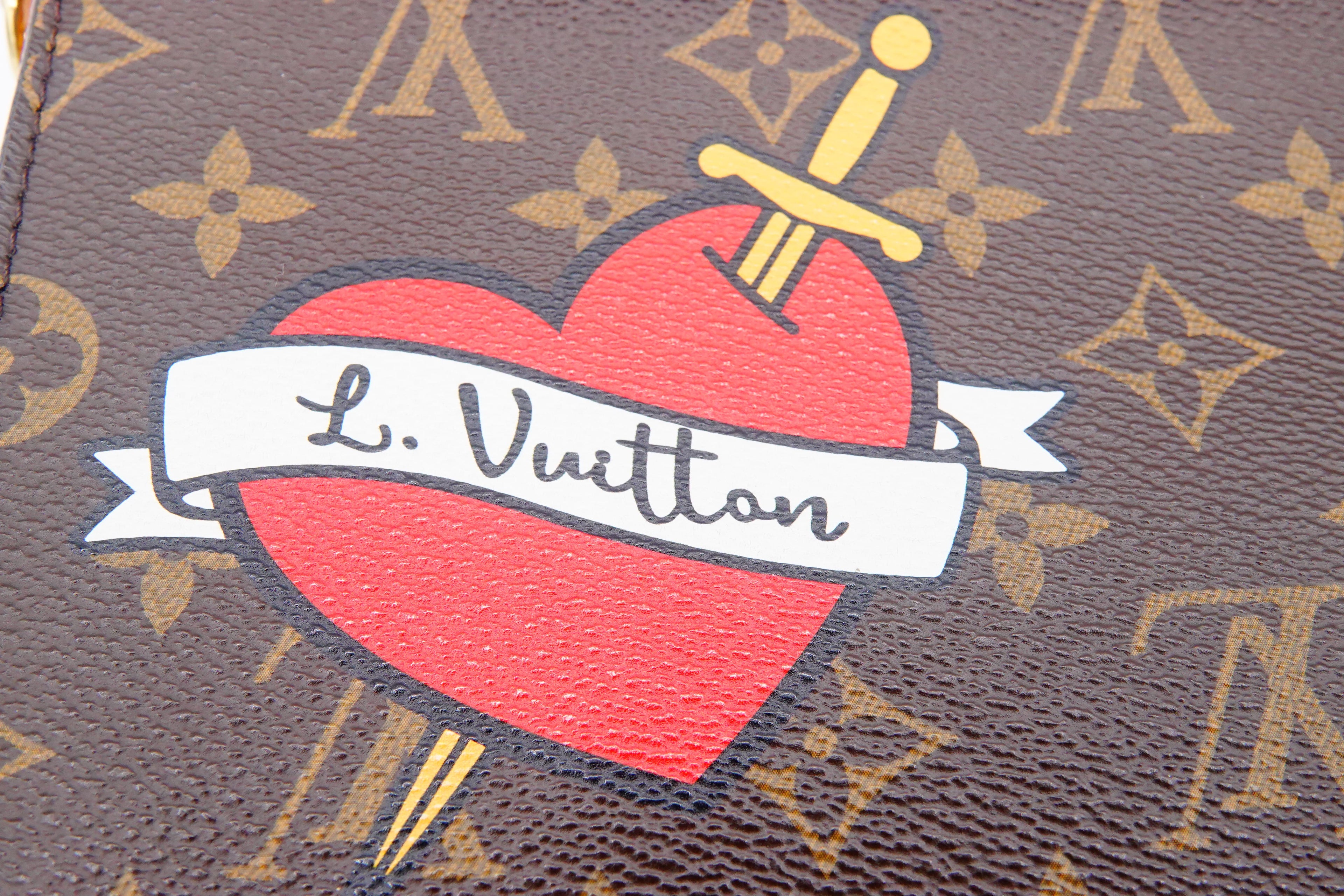 Louis Vuitton monogram bag with a red heart and sword design.