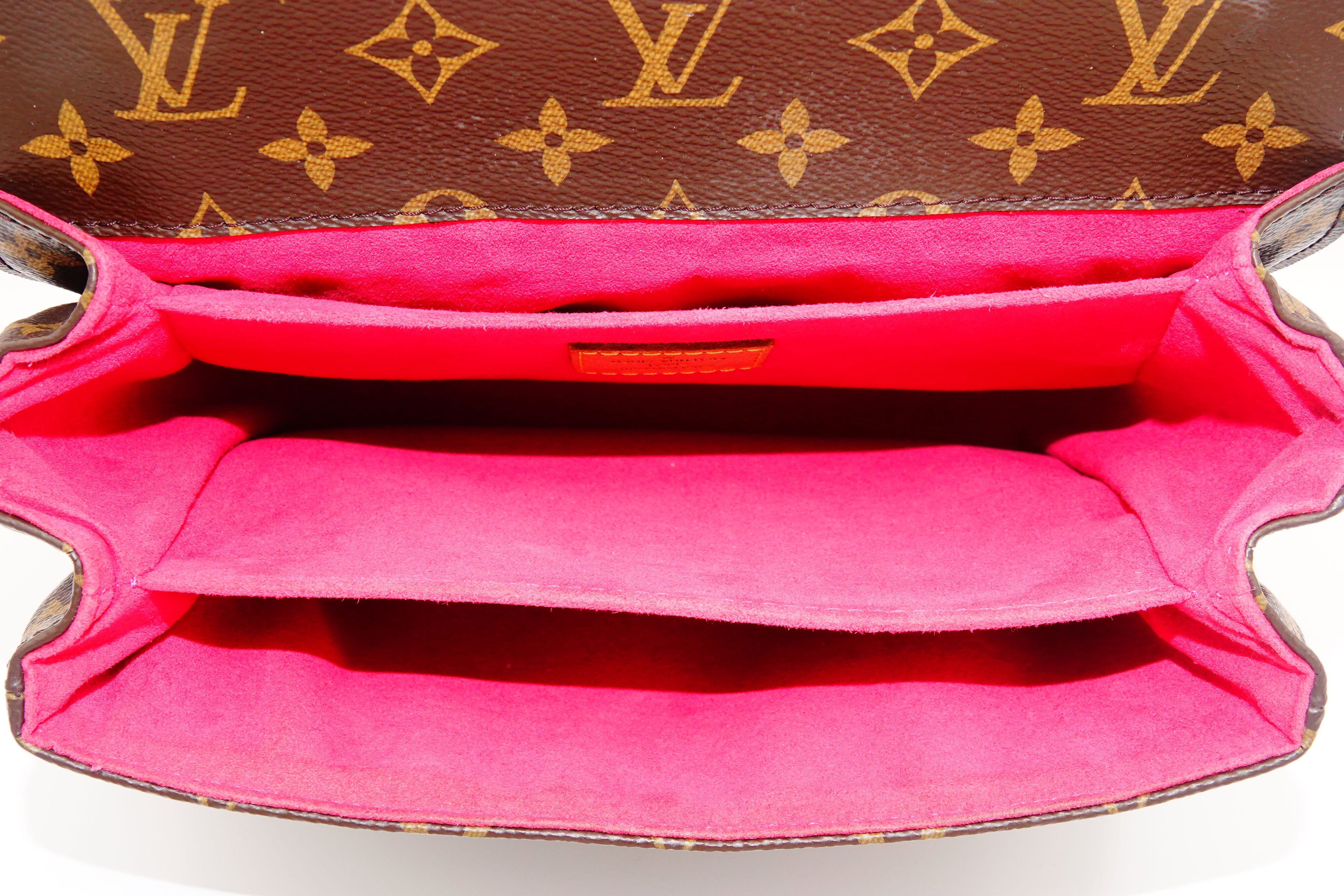 Close-up of a Louis Vuitton handbag with monogram pattern and pink interior.