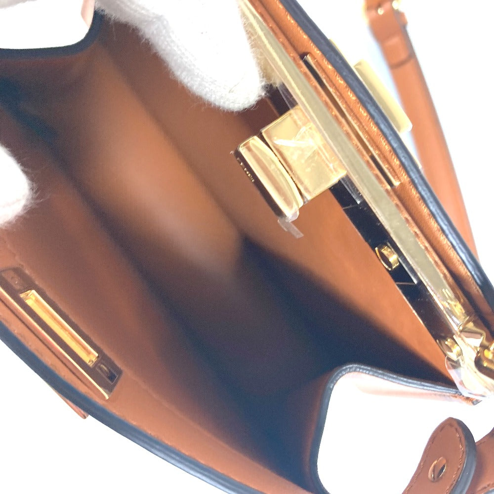 Close-up of a brown handbag with gold accents on a white background