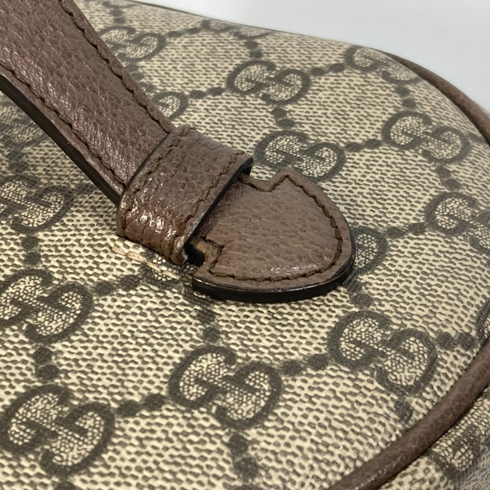 Close-up of a Gucci handbag with brown leather strap and monogram pattern.