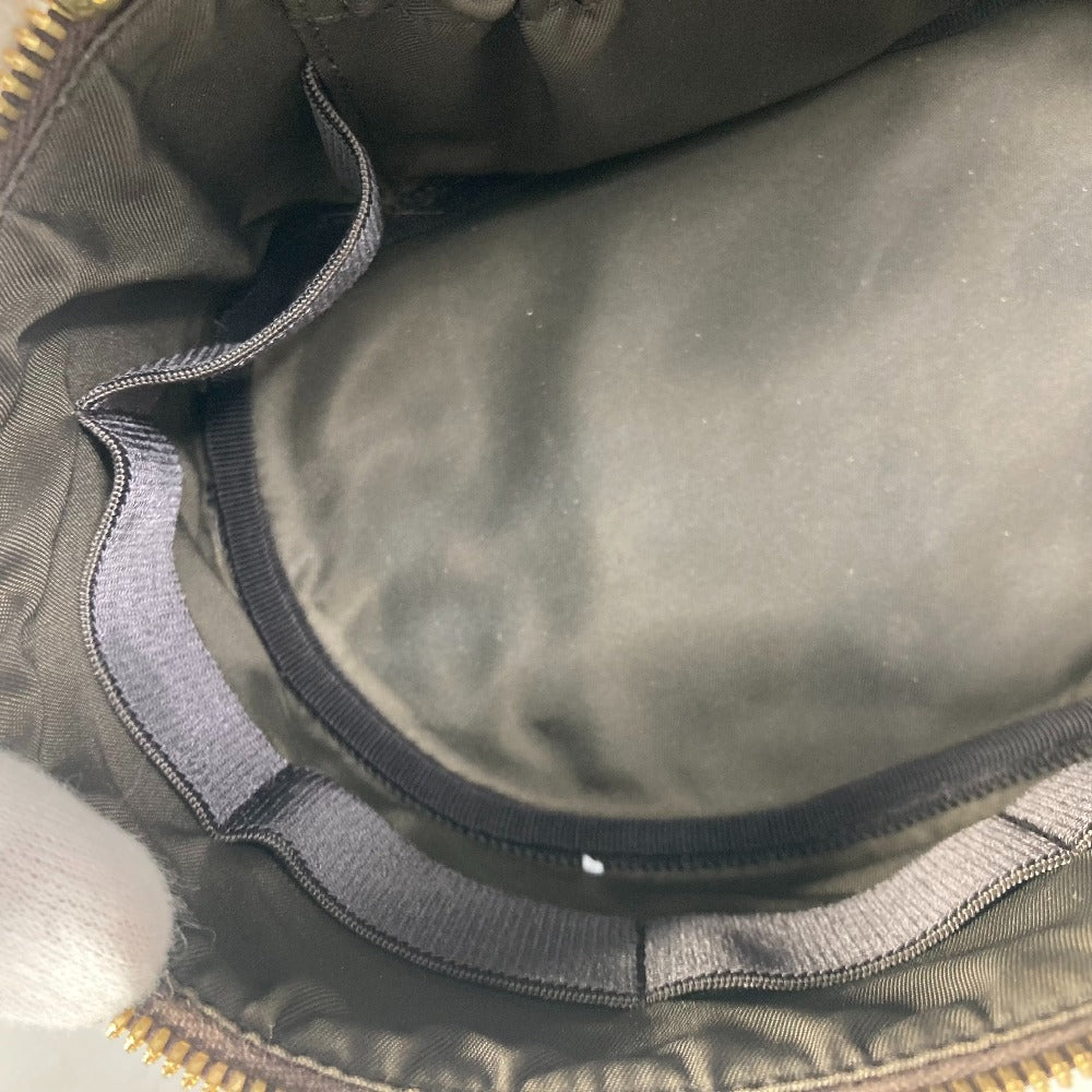Close-up of a green bag with a gold zipper, showing fabric texture and stitching details.