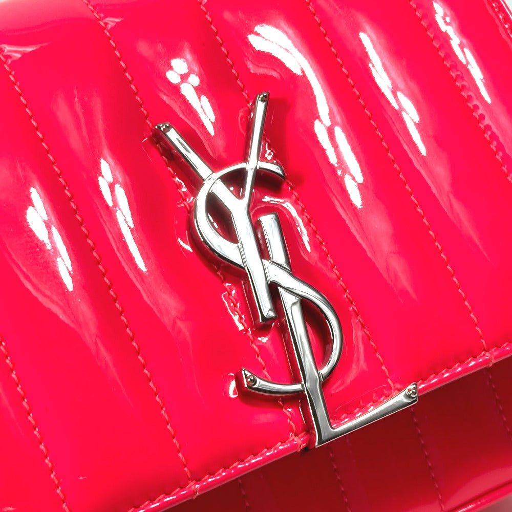 Shiny red handbag with a silver logo on a reflective surface