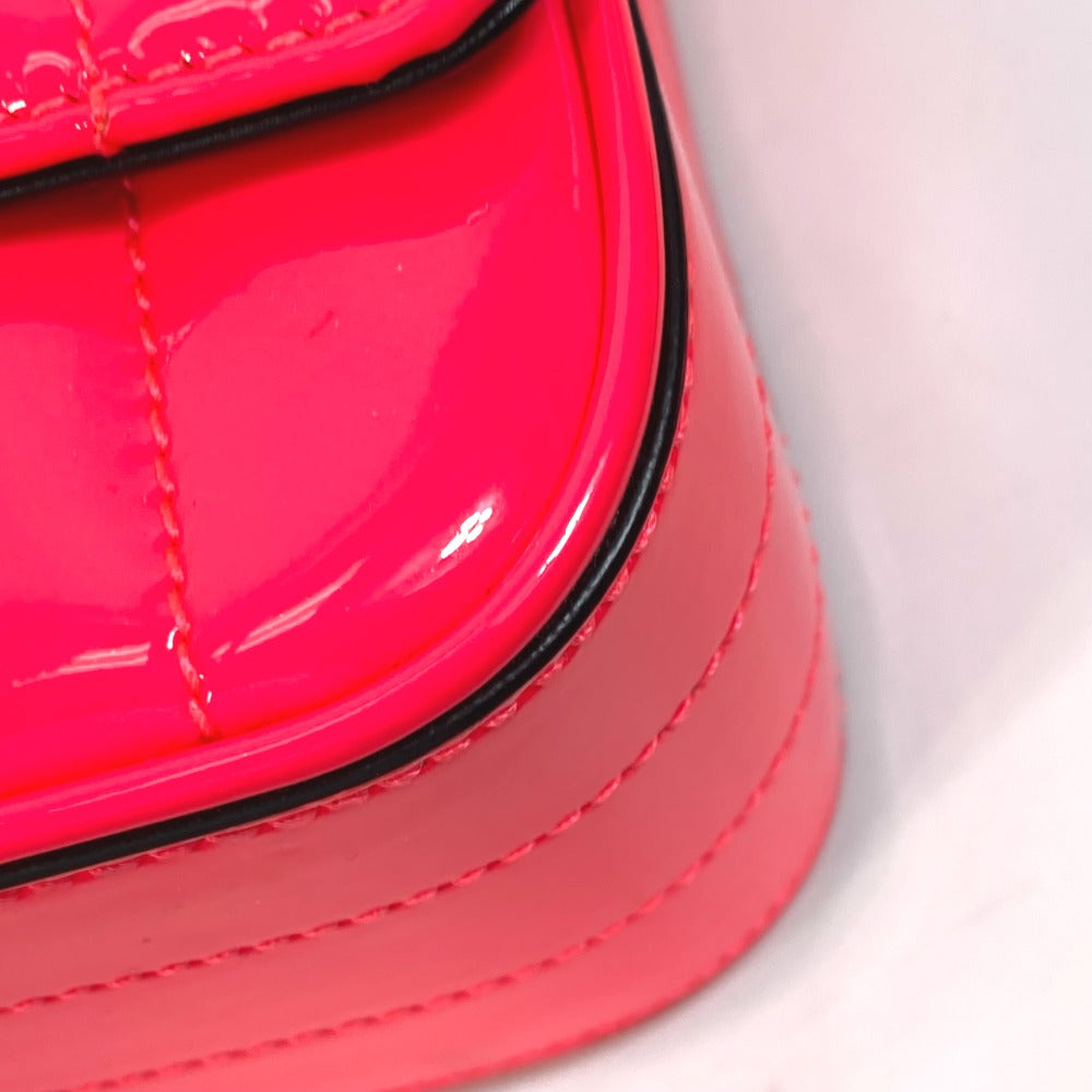 Close-up of a pink patent leather handbag with black stitching on a white background