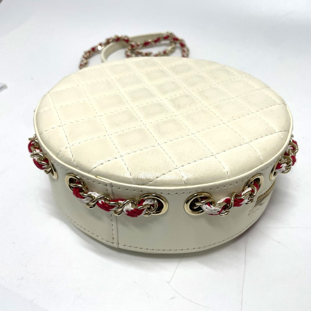 White quilted handbag with gold and red chain details on a white background