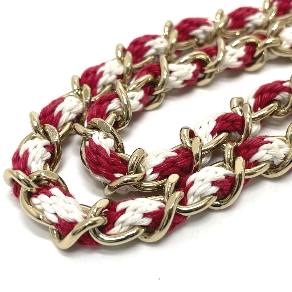 Bracelet with gold chain and red and white braided pattern on a white background