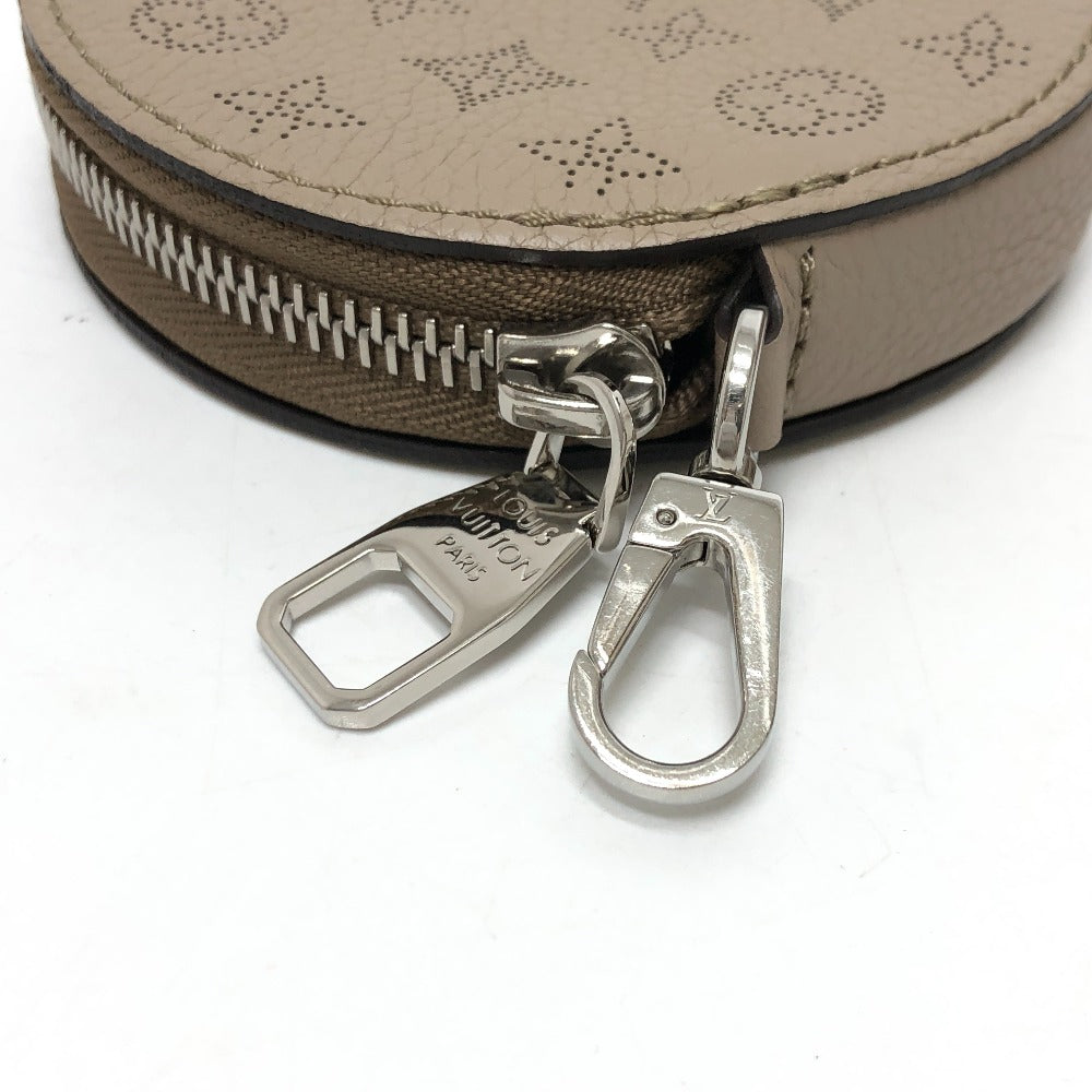 Close-up of a beige round pouch with silver zipper and carabiner on a white background