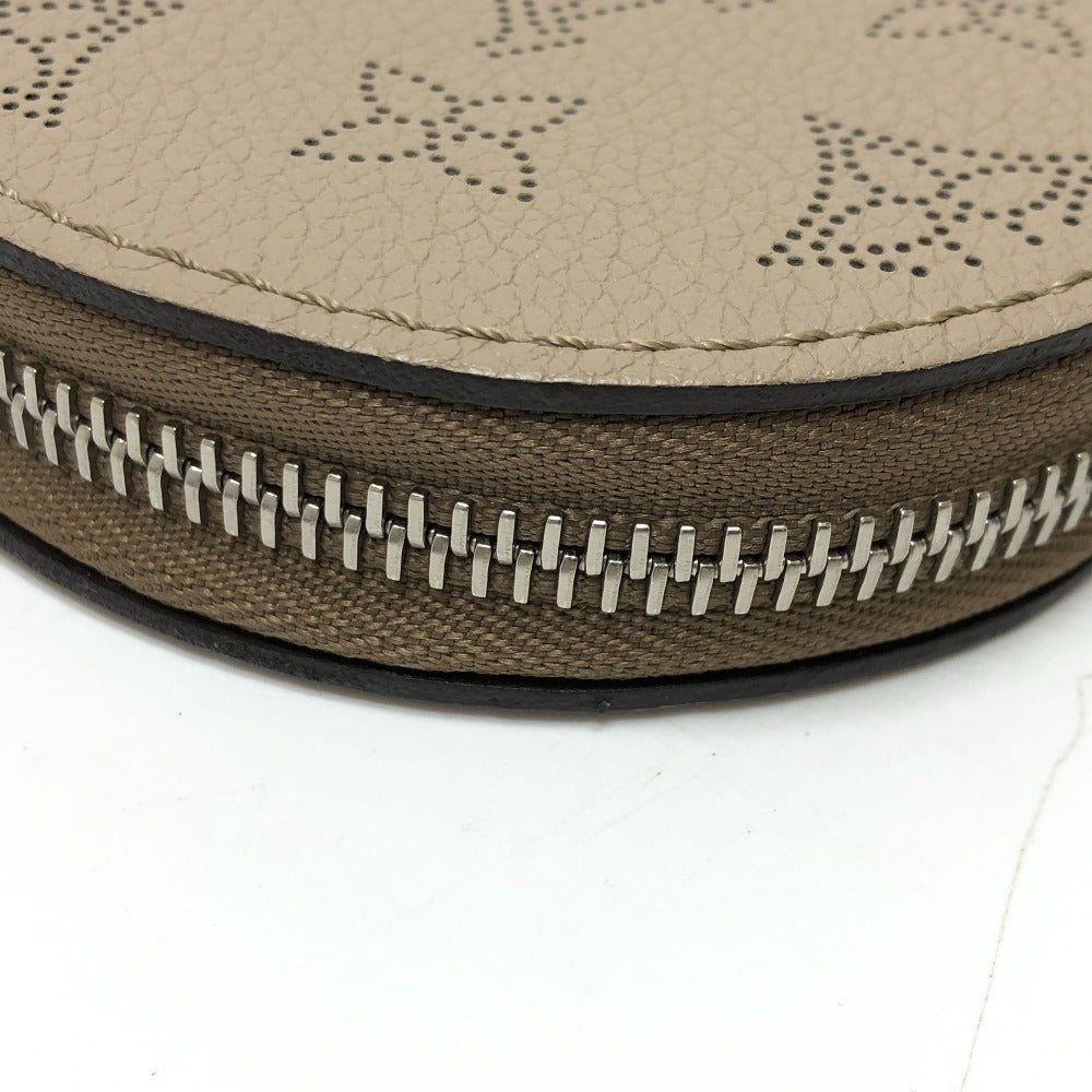Close-up of a round beige leather case with a silver zipper on a white background