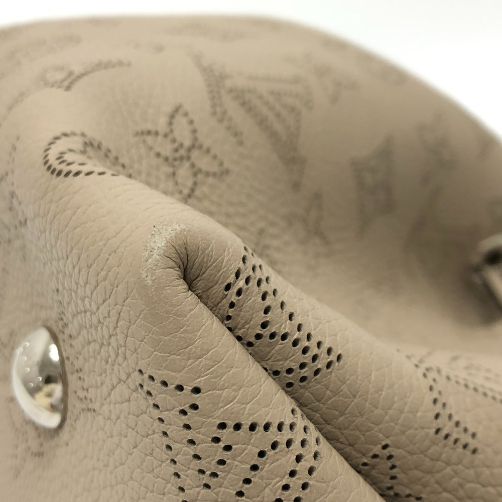 Close-up of beige leather with decorative stitching and button on a white background