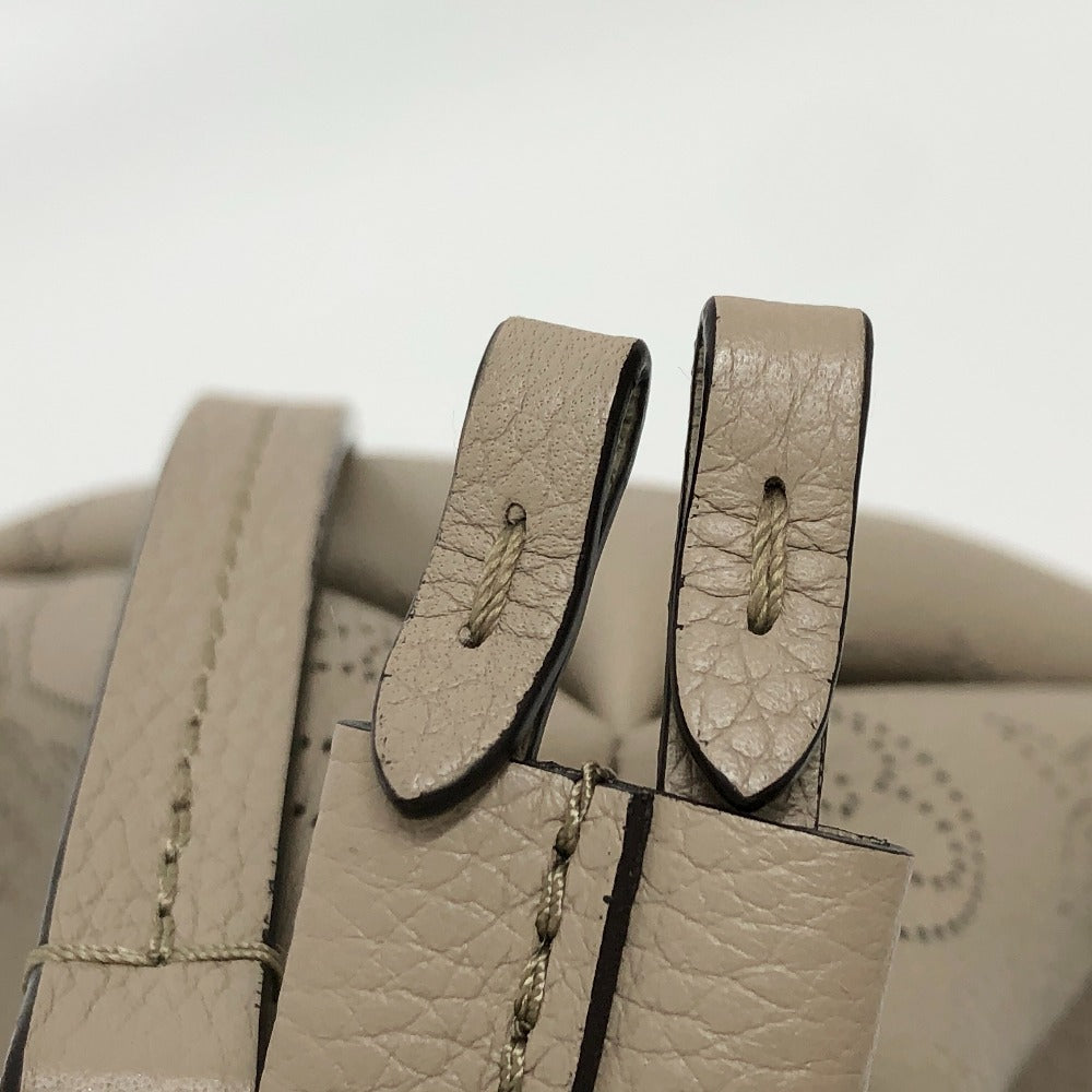 Close-up of beige leather shoes with visible stitching on a light gray background