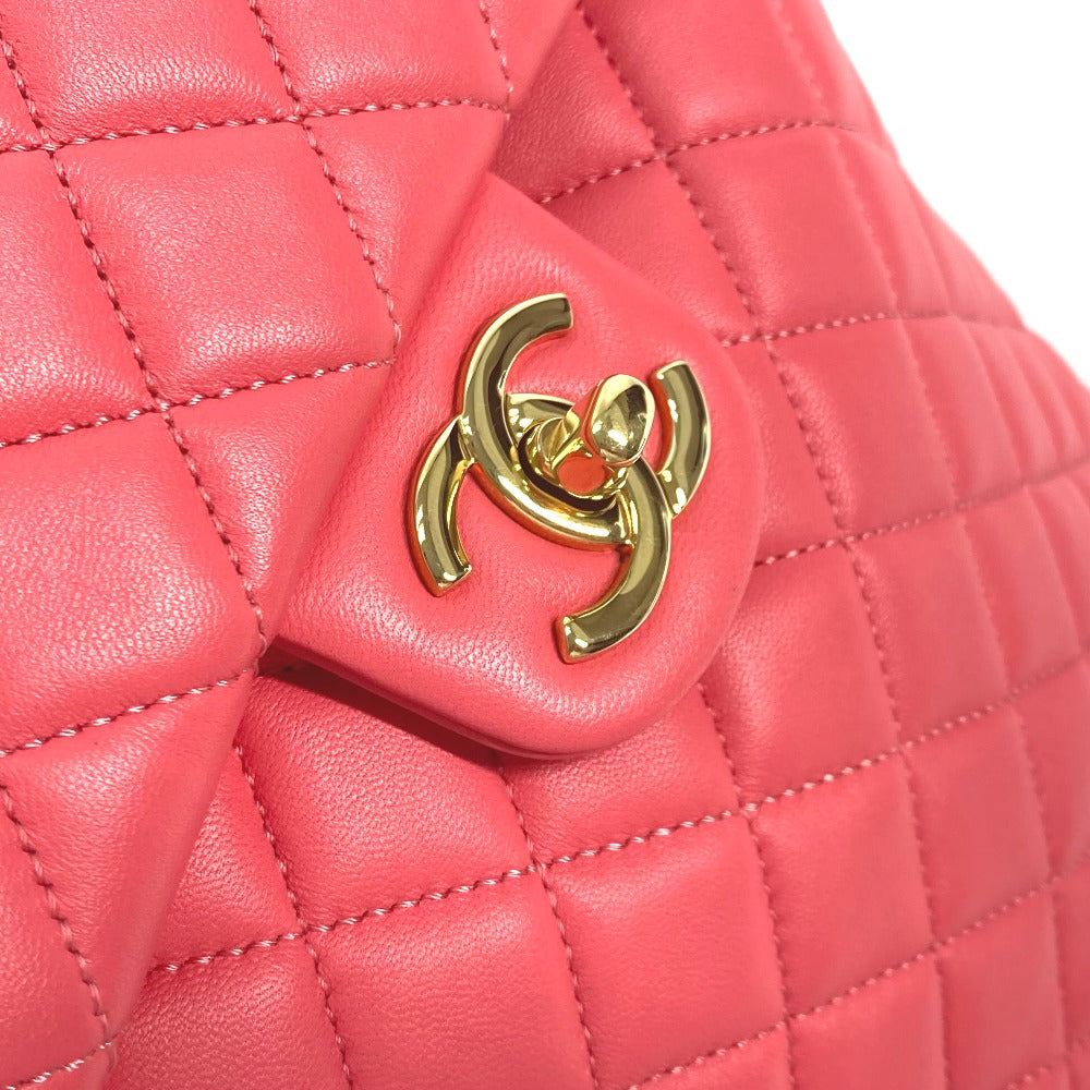 Close-up of a pink quilted handbag with a gold logo on a white background