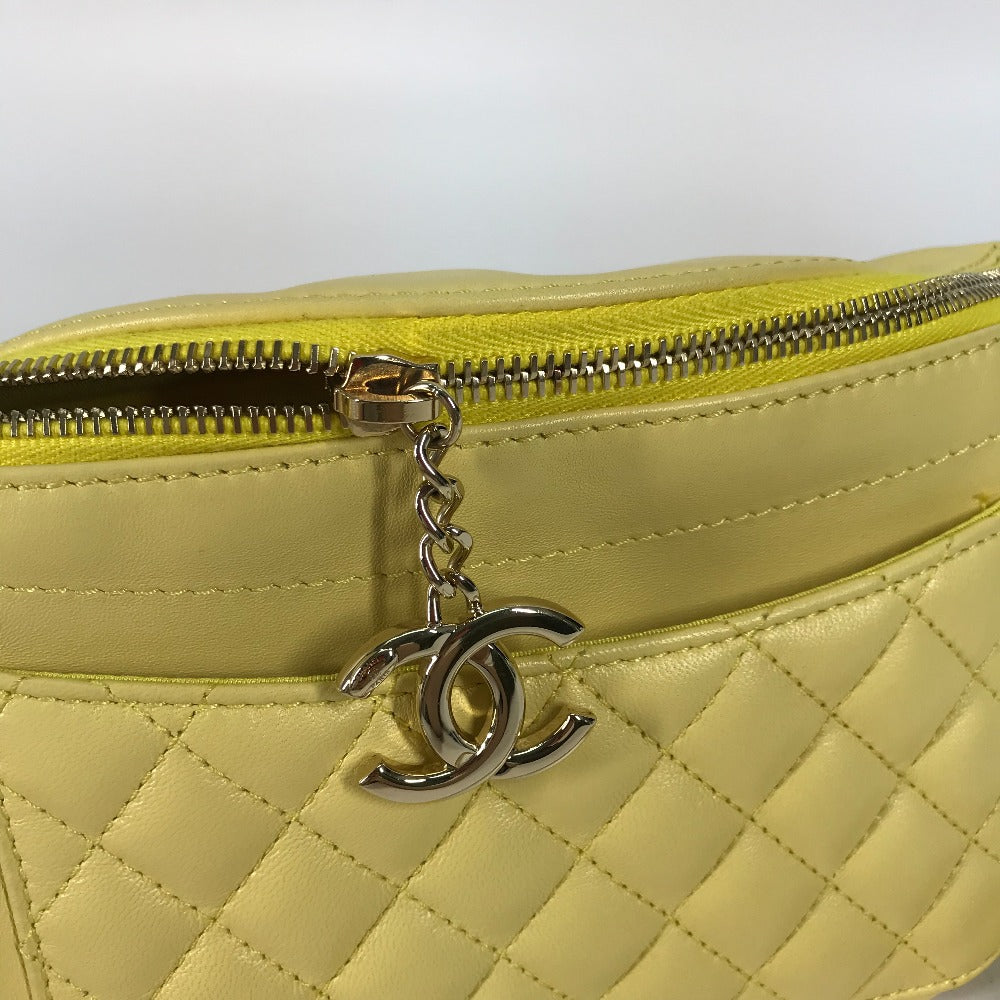 Yellow quilted handbag with a silver zipper and Chanel logo charm on a white background
