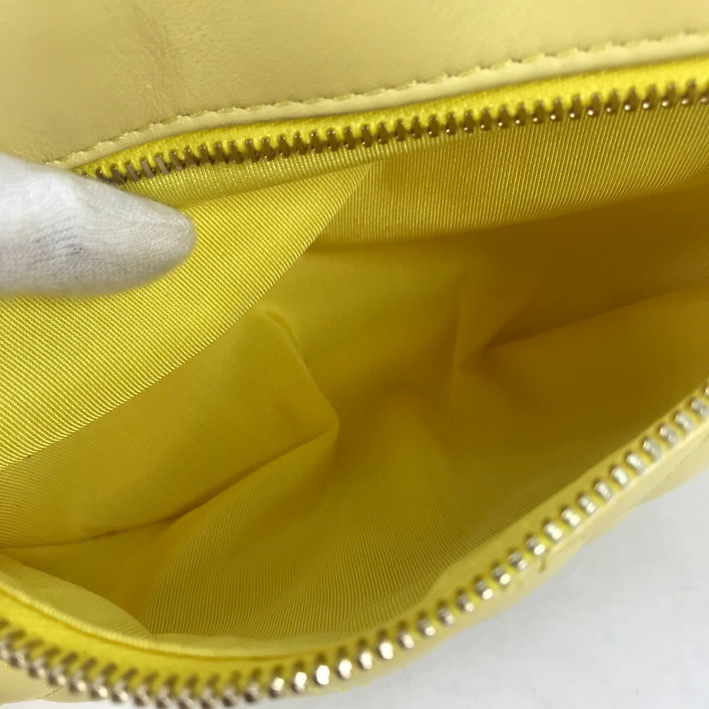 Close-up of a yellow handbag with a zipper, held by a hand.