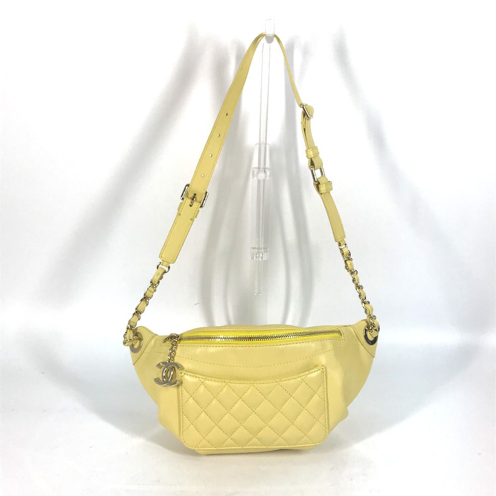 Yellow quilted handbag with chain strap on a white background