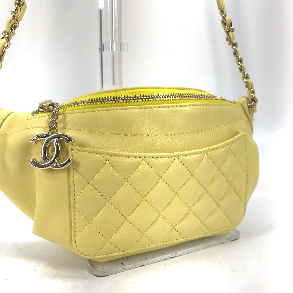 Yellow quilted handbag with a silver chain and logo on a white background