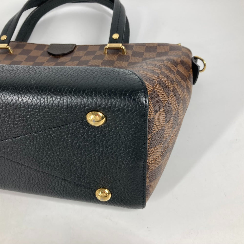 Black and brown checkered handbag with gold accents on a white background