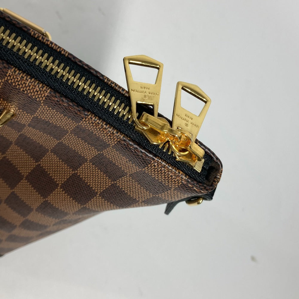 Close-up of a brown checkered handbag with gold zippers on a light gray background