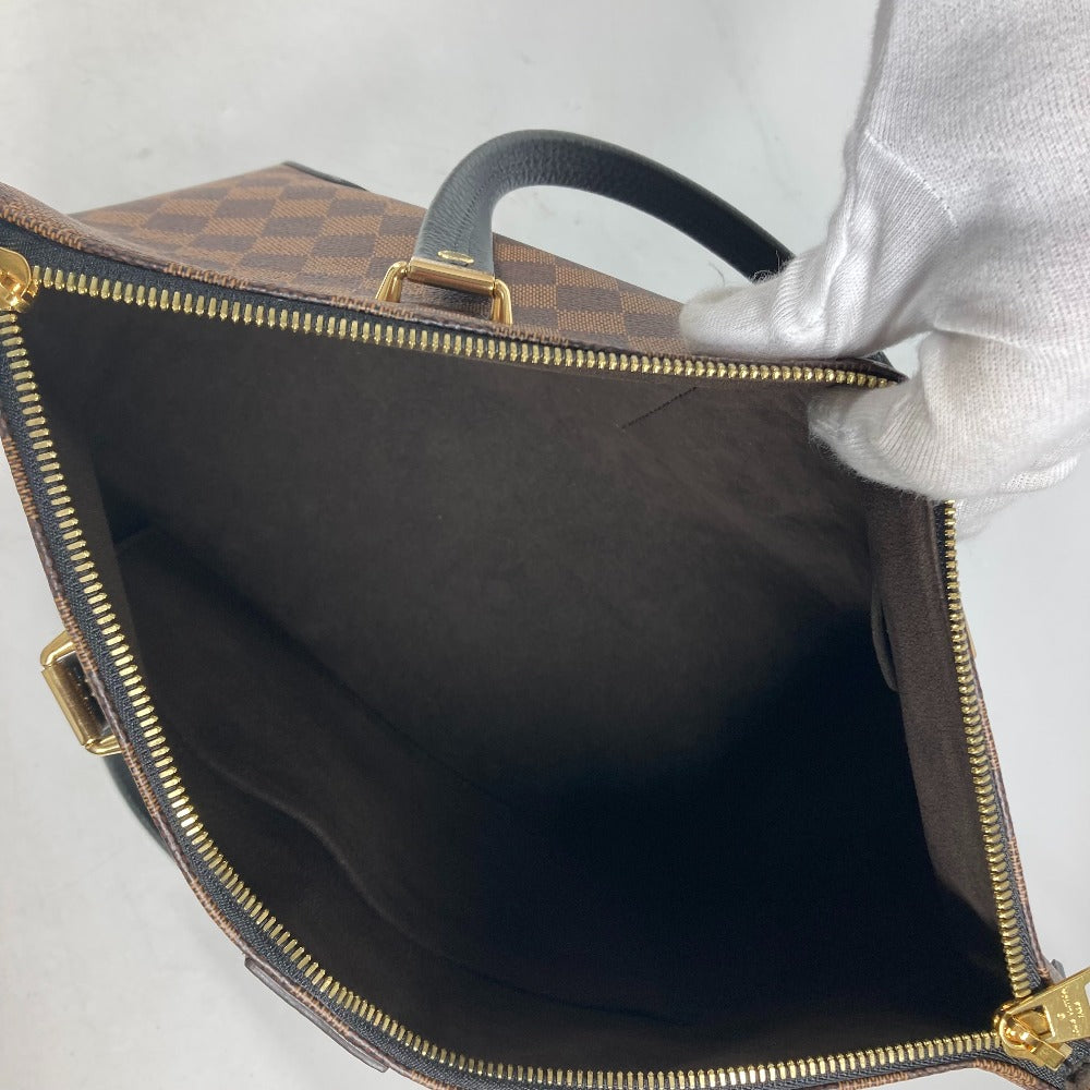 Close-up of a brown leather bag with gold zipper and hardware on a light gray background