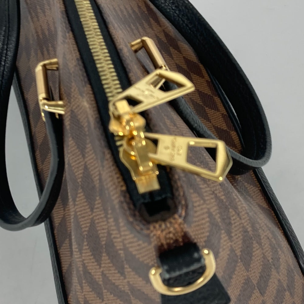 Close-up of a patterned bag with gold zipper pull and black strap.