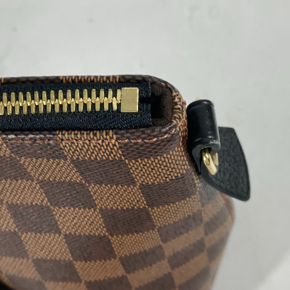 Close-up of a brown checkered handbag with gold zipper and black clasp on a light gray background