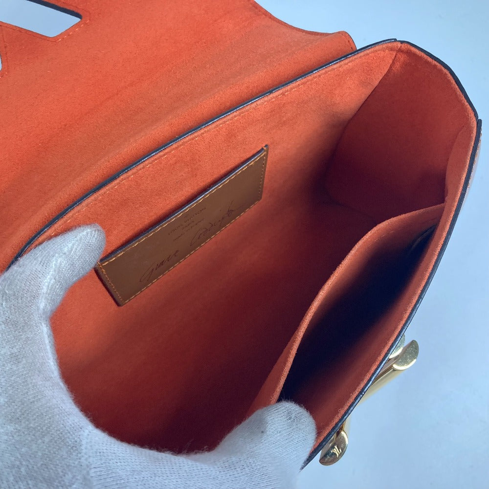 Close-up of a red handbag with a gold tag on a light blue background