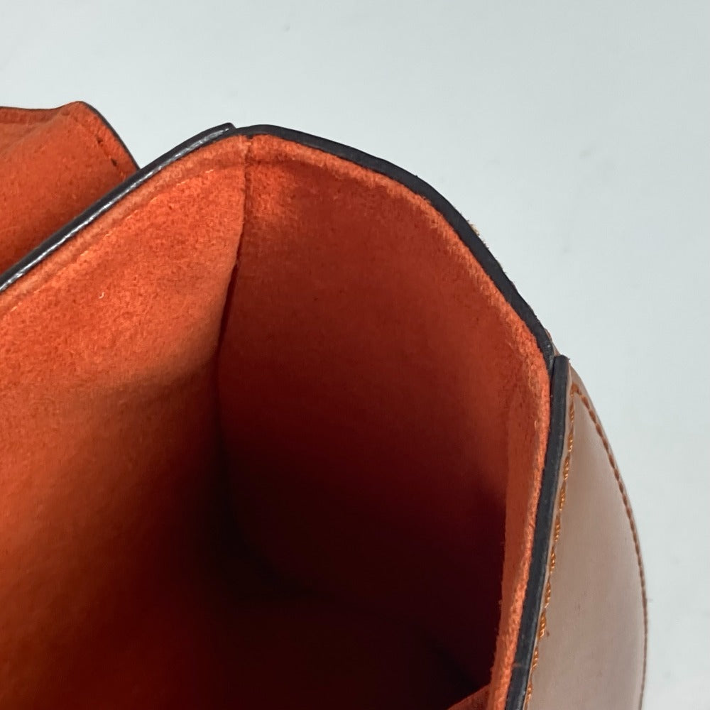 Close-up of a brown leather bag with a black interior lining on a light gray background