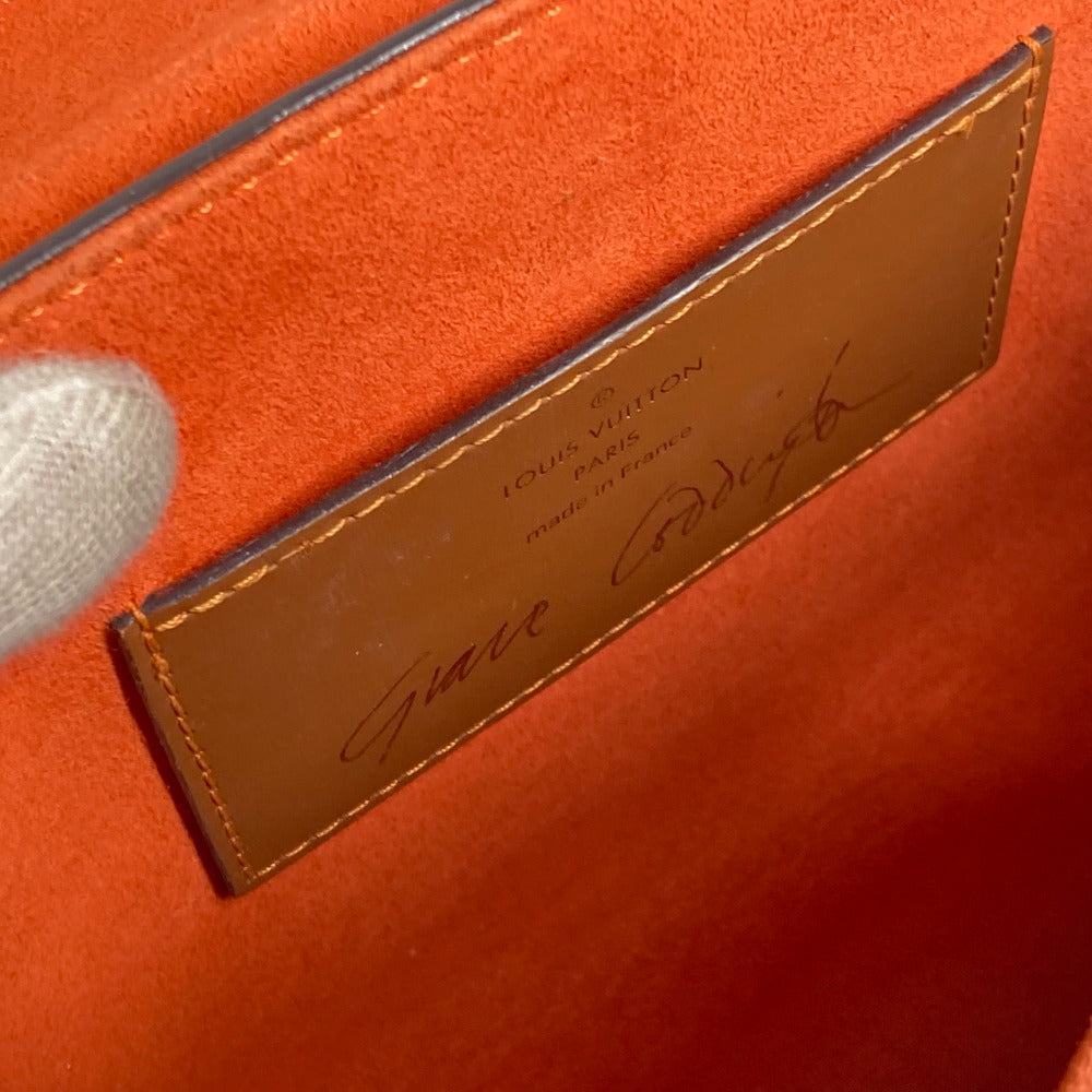 Close-up of a Louis Vuitton cardholder with a signature on an orange background