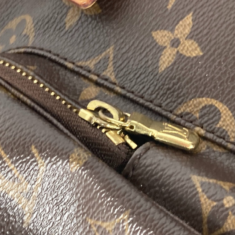 Close-up of a gold zipper on a Louis Vuitton handbag with monogram pattern.