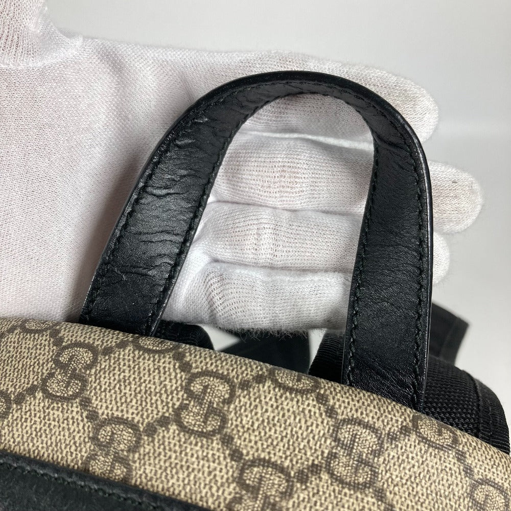 Close-up of a Gucci bag with a monogram pattern and black leather handle.