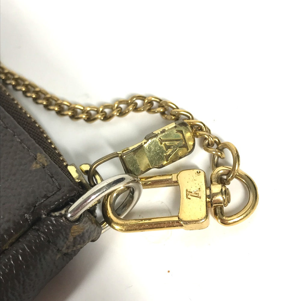 Close-up of a gold chain and clasp attached to a black leather product on a white background