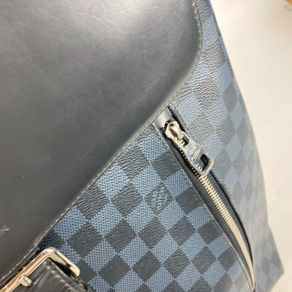 Close-up of a black leather handbag with a checkered pattern and gold zipper.