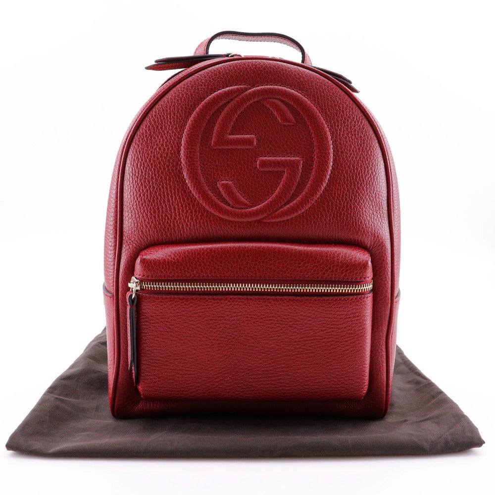 Red backpack with a logo on a brown surface