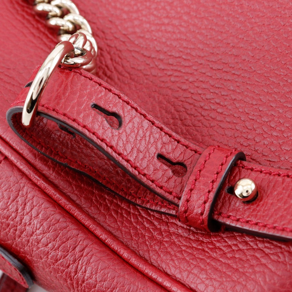 Close-up of a red leather handbag with gold chain detail