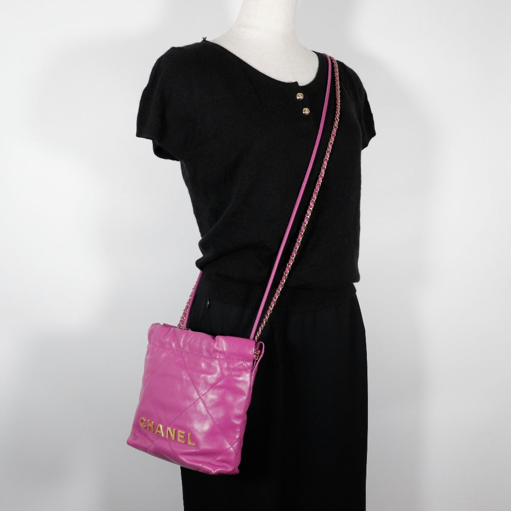 Pink Chanel handbag with a black dress on a white background