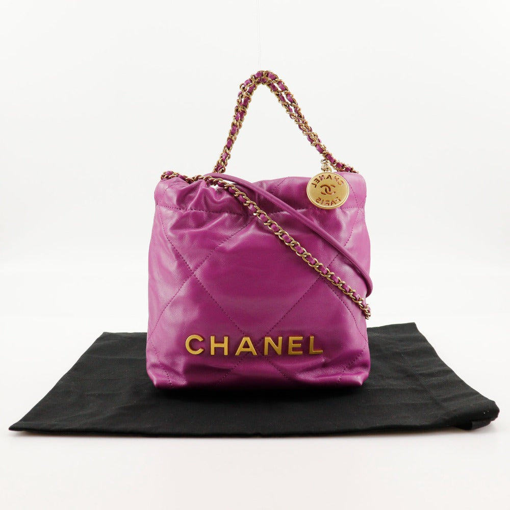 Pink Chanel handbag with gold chain on a black mat against a white background